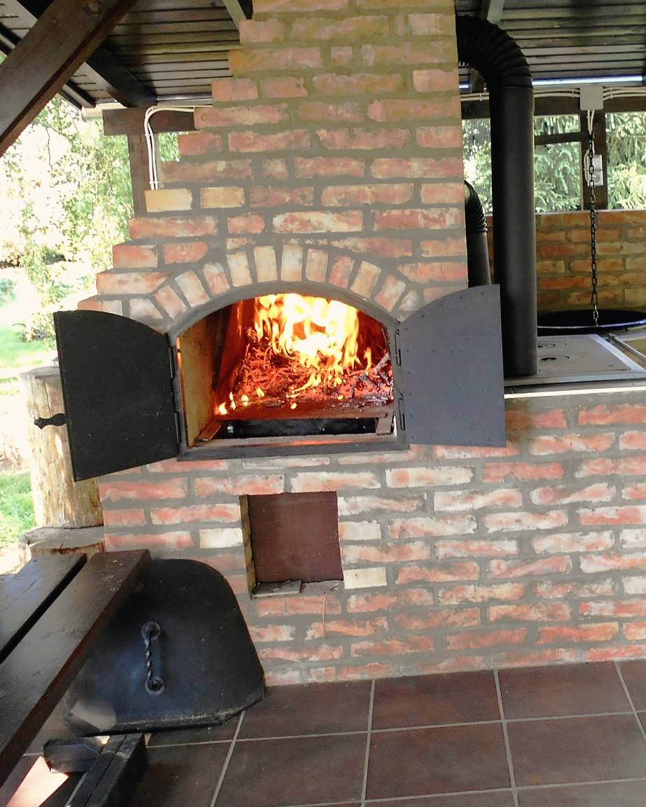 Közelkép a téglakemencéről, a nyitott ajtó mögött ég a tűz.
