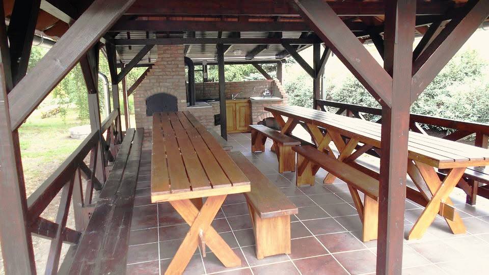 A fedett pavilon padsorai, mögötte a téglakemence és a zöld udvar.